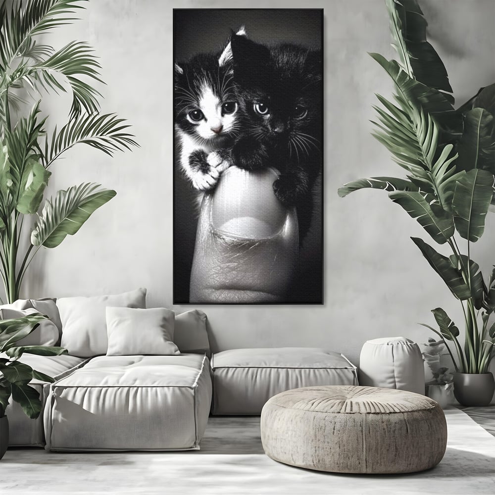 Tablou canvas cu tablou canvas cu doi pisoi mici agatati de un deget, in rama de aluminiu negru, pe perete intr-un living